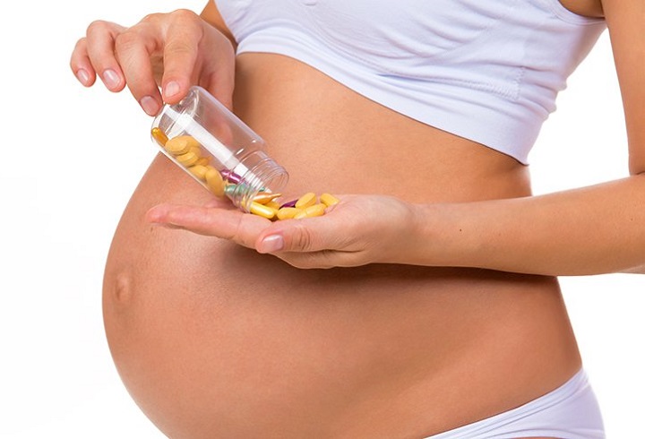 Беременная принимает витамины 