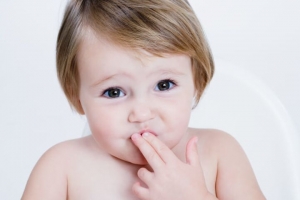 Ребенок держит пальцы у рта